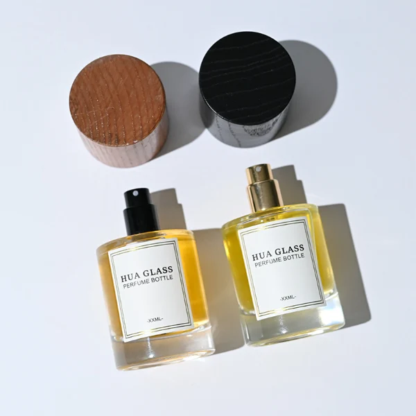 HUA0296 perfume bottle, cylindrical transparent colorless glass body with thick base and smooth rounded silhouette, 30 ml, 50 ml, or 100 ml liquid, cylindrical wooden cap in natural wood or matte black finish, printed label attached on bottle surface, modern minimalist luxury design, ideal for gifting and daily use.
