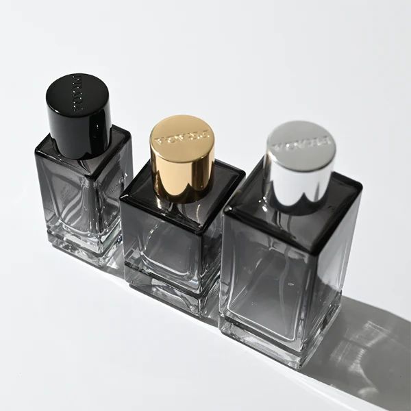HUA0298 perfume bottle, gradient semi-transparent glass body with thick base and curved side contours, 30 ml, 50 ml, or 100 ml liquid, glossy cylindrical aluminum cap in black, silver, or gold finish, printed logo on bottle surface, modern minimalist luxury design, ideal for gifting and daily use.
