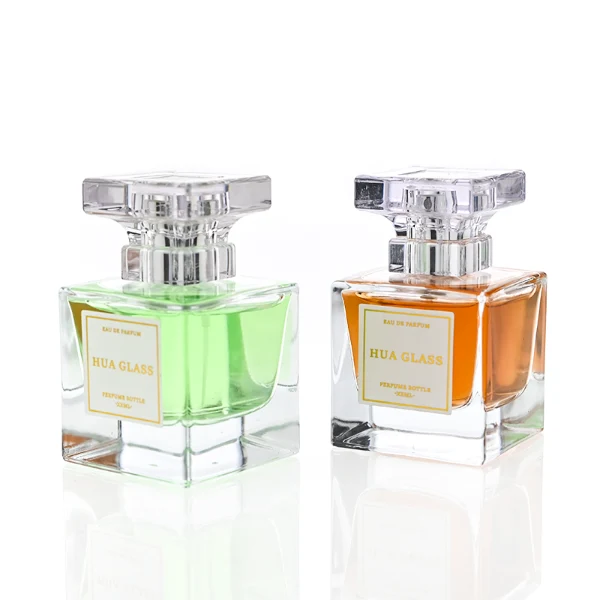 HUA0300 perfume bottle, rectangular transparent colorless glass body with thick base and smooth surface, 30 ml, 50 ml, or 100 ml liquid, flat multifaceted plastic cap with silver bottle neck, printed label attached on bottle surface, modern elegant luxury design, ideal for gifting and daily use.