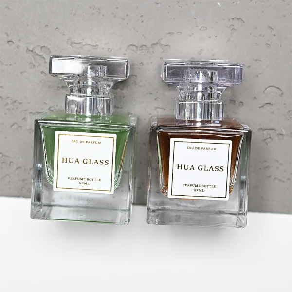 HUA0300 perfume bottle, rectangular transparent colorless glass body with thick base and smooth surface, 30 ml, 50 ml, or 100 ml liquid, flat multifaceted plastic cap with silver bottle neck, printed label attached on bottle surface, modern elegant luxury design, ideal for gifting and daily use.
