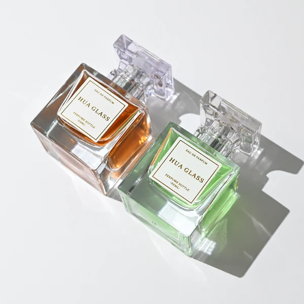 HUA0300 perfume bottle, rectangular transparent colorless glass body with thick base and smooth surface, 30 ml, 50 ml, or 100 ml liquid, flat multifaceted plastic cap with silver bottle neck, printed label attached on bottle surface, modern elegant luxury design, ideal for gifting and daily use.