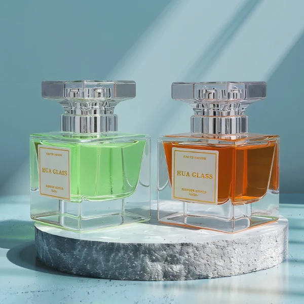 HUA0300 perfume bottle, rectangular transparent colorless glass body with thick base and smooth surface, 30 ml, 50 ml, or 100 ml liquid, flat multifaceted plastic cap with silver bottle neck, printed label attached on bottle surface, modern elegant luxury design, ideal for gifting and daily use.