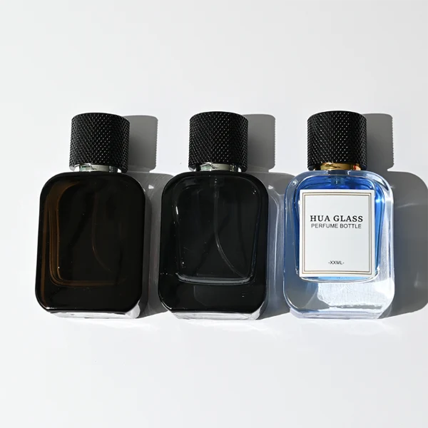 HUA0302 perfume bottle, rounded rectangular glass body with thick base in transparent, semi-transparent black, or amber color, 30 ml, 50 ml, or 100 ml liquid, cylindrical plastic cap with gold or silver bottle neck, printed logo or blank bottle surface, modern minimalist luxury design, ideal for gifting and daily use.
