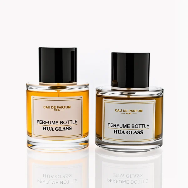 HUA0303 perfume bottle, cylindrical transparent colorless glass body with thick rounded base and smooth curved silhouette, 30 ml, 50 ml, or 100 ml liquid, glossy black cylindrical aluminum cap with flat top, printed label attached on bottle surface, modern minimalist luxury design, ideal for gifting and daily use.