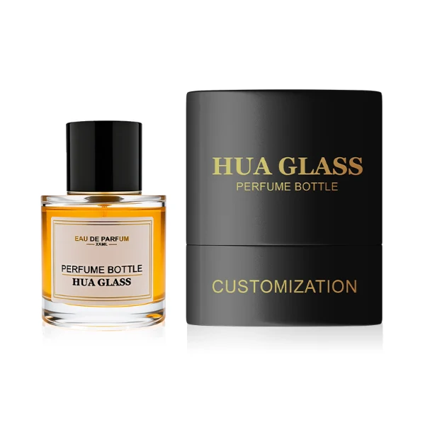 HUA0303 perfume bottle, cylindrical transparent colorless glass body with thick rounded base and smooth curved silhouette, 30 ml, 50 ml, or 100 ml liquid, glossy black cylindrical aluminum cap with flat top, printed label attached on bottle surface, modern minimalist luxury design, ideal for gifting and daily use.
