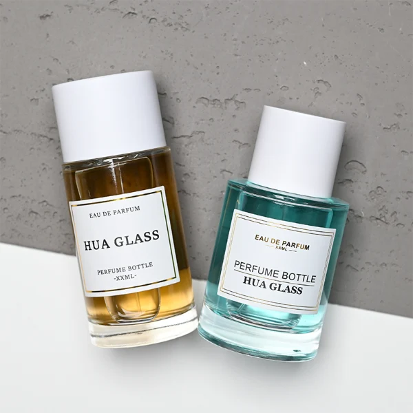 HUA0304 perfume bottle, cylindrical transparent colorless glass body with thick rounded base and smooth curved silhouette, 30 ml, 50 ml, or 100 ml liquid, glossy white cylindrical plastic cap with flat top, printed label attached on bottle surface, modern minimalist luxury design, ideal for gifting and daily use.