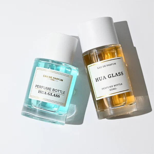 HUA0304 perfume bottle, cylindrical transparent colorless glass body with thick rounded base and smooth curved silhouette, 30 ml, 50 ml, or 100 ml liquid, glossy white cylindrical plastic cap with flat top, printed label attached on bottle surface, modern minimalist luxury design, ideal for gifting and daily use.