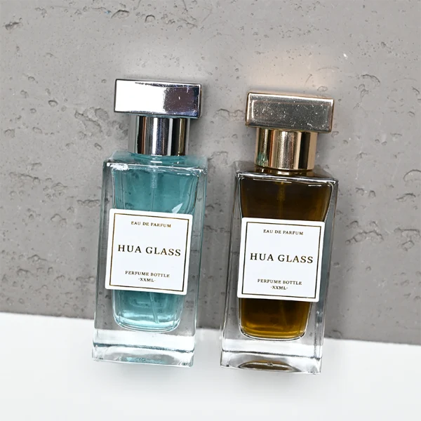 HUA0306 perfume bottle, rectangular transparent colorless or semi-transparent gradient black glass body with thick base and sharp edges, 30 ml, 50 ml, or 100 ml liquid, glossy T-shaped Zamac cap in silver, gold, or black finish, printed label or logo on bottle surface, modern luxury minimalist design, ideal for gifting and daily use.