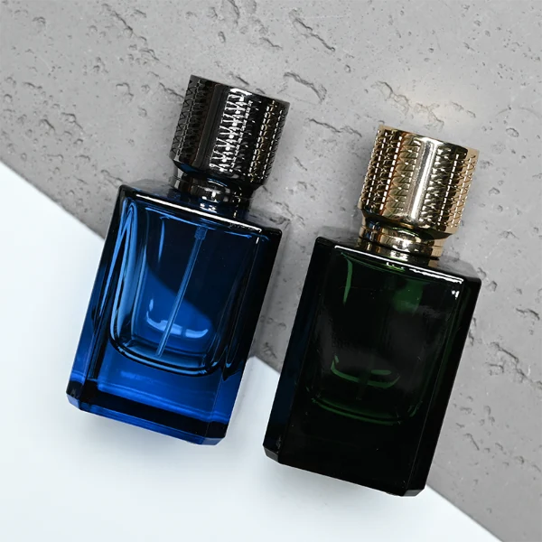 HUA0308 perfume bottle, semi-transparent blue or dark green customizable glass body with thick base and clean rectangular silhouette, 30 ml, 50 ml, or 100 ml liquid, textured cylindrical plastic cap in gold or black finish, gold or white printed logo on bottle surface, modern masculine luxury design, ideal for gifting and daily use.