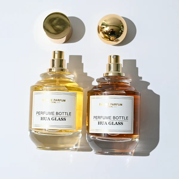 HUA0309 perfume bottle, rounded transparent colorless glass body with thick base and smooth curved silhouette, 100 ml liquid, glossy Zamac cap in cylindrical or spherical shape, printed label attached on bottle surface, elegant modern luxury design, ideal for gifting and daily use.