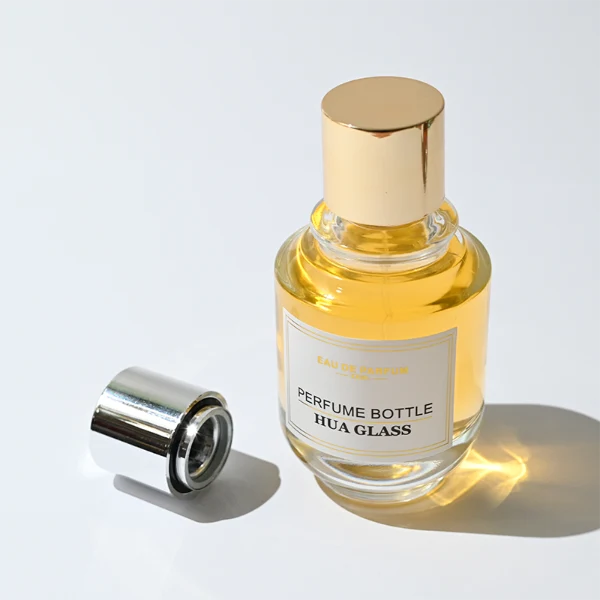 HUA0309 perfume bottle, rounded transparent colorless glass body with thick base and smooth curved silhouette, 100 ml liquid, glossy Zamac cap in cylindrical or spherical shape, printed label attached on bottle surface, elegant modern luxury design, ideal for gifting and daily use.
