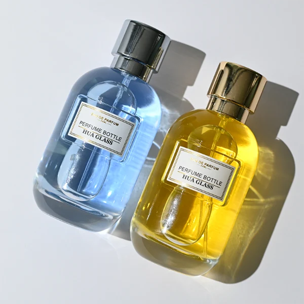 HUA0310 perfume bottle, rounded transparent colorless glass body with thick base and smooth curved silhouette, 100 ml liquid, glossy cylindrical Zamac cap with matching gold or silver metallic gloss bottle neck, printed label attached on bottle surface, modern minimalist luxury design, ideal for gifting and daily use.