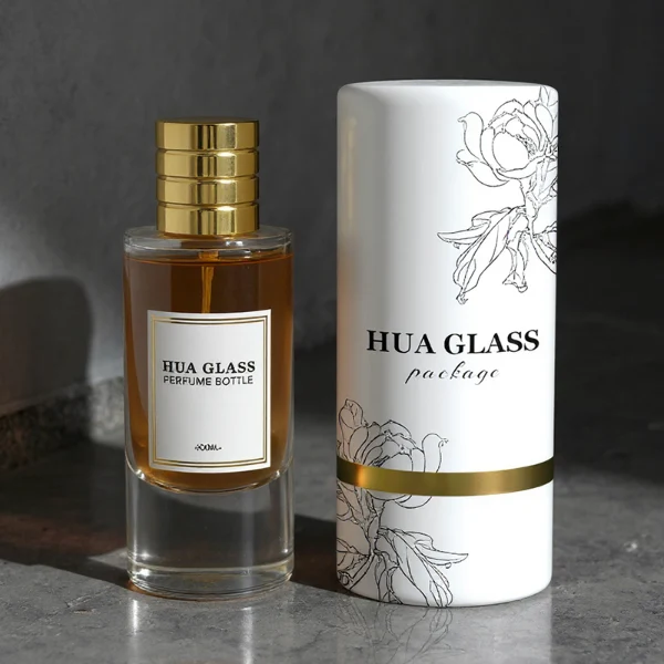HUA0311 perfume bottle, cylindrical transparent colorless glass body with thick rounded base and smooth curved silhouette, 80 ml liquid, layered cylindrical plastic cap with ring groove details in gold or black finish, printed label attached on bottle surface, modern minimalist luxury design, ideal for gifting and daily use.