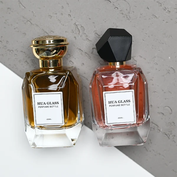 HUA0312 perfume bottle, transparent colorless multifaceted angular-cut glass body with thick geometric base, 100 ml liquid, multifaceted spherical or layered bowl-shaped plastic cap with gold bottle neck, printed label attached on bottle surface, elegant modern luxury design, ideal for gifting and daily use.