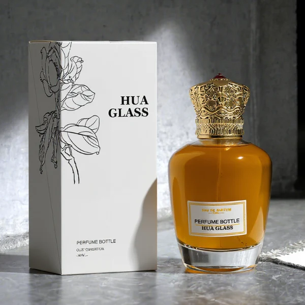 HUA0314 perfume bottle, rounded transparent colorless glass body with thick base and smooth curved silhouette, 100 ml liquid, ornamental Zamak cap with carved crown-inspired or layered dome design in glossy gold finish, printed label attached on bottle surface, vintage royal luxury design, ideal for gifting and daily use.