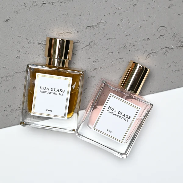 HUA0316 perfume bottle, square transparent colorless glass body with thick base and sharp edges, 30 ml, 50 ml, or 100 ml liquid, straight cylindrical Zinc Alloy cap or cylindrical cap with glossy gold bottle neck, printed label attached on bottle surface, modern minimalist luxury design, ideal for gifting and daily use.