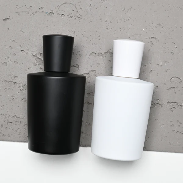 HUA0317 perfume bottle, cylindrical matte black, matte white, or transparent colorless glass body with thick rounded base, 50 ml or 70 ml liquid, flared cylindrical plastic cap in black, white, or gold finish, printed logo or brand label on bottle surface, modern minimalist fashion design, ideal for gifting and daily use.
