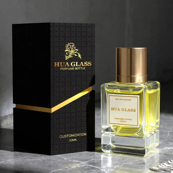 HUA0318 perfume bottle, rectangular transparent colorless glass body with thick base and sharp edges, 30 ml, 50 ml, or 100 ml liquid, glossy cylindrical aluminum cap in gold or black finish, printed label attached on bottle surface, modern minimalist luxury design, ideal for gifting and daily use.