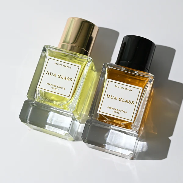 HUA0318 perfume bottle, rectangular transparent colorless glass body with thick base and sharp edges, 30 ml, 50 ml, or 100 ml liquid, glossy cylindrical aluminum cap in gold or black finish, printed label attached on bottle surface, modern minimalist luxury design, ideal for gifting and daily use.