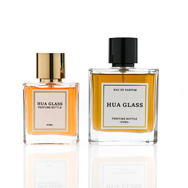 HUA0320 perfume bottle, square transparent colorless glass body with thick base and sharp edges, 50 ml or 100 ml liquid, straight cylindrical Zamac cap in glossy gold or black finish with matching bottle neck, printed label attached on bottle surface, modern minimalist luxury design, ideal for gifting and daily use.