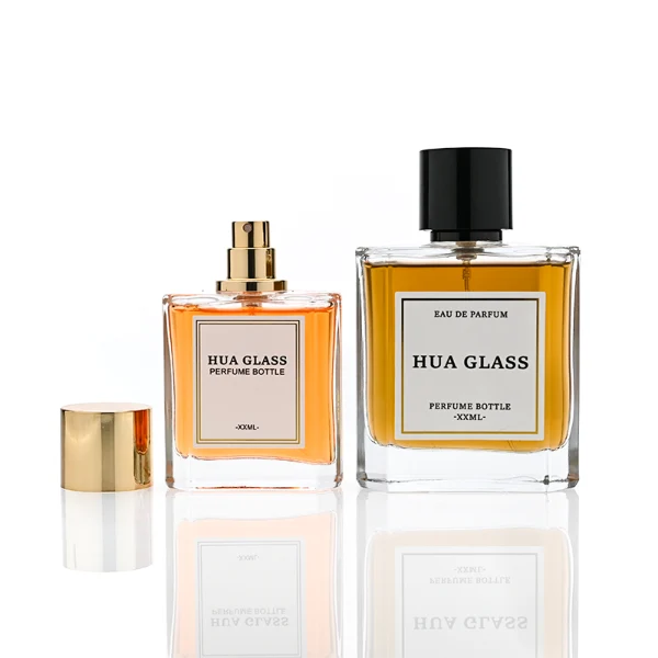 HUA0320 perfume bottle, square transparent colorless glass body with thick base and sharp edges, 50 ml or 100 ml liquid, straight cylindrical Zamac cap in glossy gold or black finish with matching bottle neck, printed label attached on bottle surface, modern minimalist luxury design, ideal for gifting and daily use.