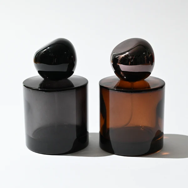 HUA0321 perfume bottle, cylindrical semi-transparent amber or black glass body with thick rounded base, 30 ml, 50 ml, or 100 ml liquid, glossy spherical plastic cap in black or dark purple color, clean blank bottle design, modern artistic minimalist style, ideal for gifting and daily use.