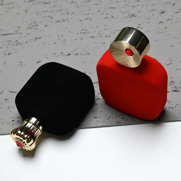 HUA0323 perfume bottle, rounded rectangular matte red or matte black glass body with thick base, 30 ml, 50 ml, or 100 ml liquid, decorative Zamac cap with engraved radial texture or crown-inspired design and jewel detail, aluminum label/sticker attached on bottle surface, artistic luxury vintage style, ideal for gifting and display.
