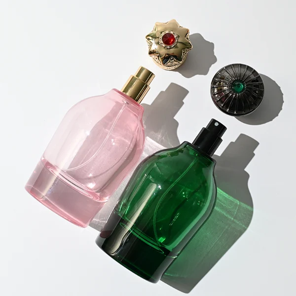 HUA0324 perfume bottle, rounded cylindrical semi-transparent red, blue, or smoky black glass body with thick base, 100 ml liquid, decorative Zamac cap with carved crown-inspired or layered dome design, metallic gold printed logo on bottle surface, vintage luxury artistic style, ideal for gifting and display.