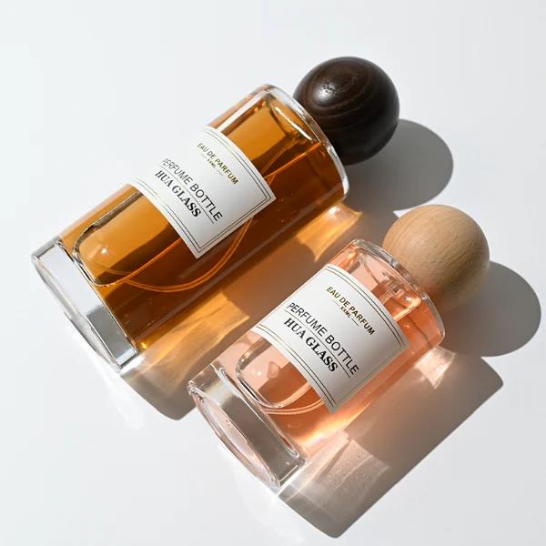 HUA0325 perfume bottle, cylindrical transparent colorless glass body with thick rounded base and smooth silhouette, 30 ml, 50 ml, 100 ml, 200 ml, or 250 ml liquid, spherical wooden cap with natural wood grain texture in light or dark finish, printed label attached on bottle surface, natural modern minimalist design, ideal for gifting and display.