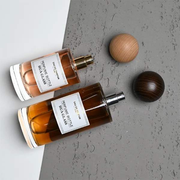 HUA0325 perfume bottle, cylindrical transparent colorless glass body with thick rounded base and smooth silhouette, 30 ml, 50 ml, 100 ml, 200 ml, or 250 ml liquid, spherical wooden cap with natural wood grain texture in light or dark finish, printed label attached on bottle surface, natural modern minimalist design, ideal for gifting and display.