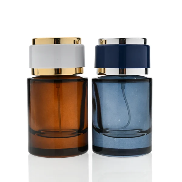 HUA0326 perfume bottle, rounded cylindrical semi-transparent smoky black, amber brown, or blue glass body with thick base, 30 ml, 50 ml, or 100 ml liquid, layered cylindrical plastic cap with black, white, or blue center section and glossy gold or silver accents on both ends, optional metallic gold printed logo or blank bottle surface, modern minimalist luxury design, ideal for gifting and daily use.