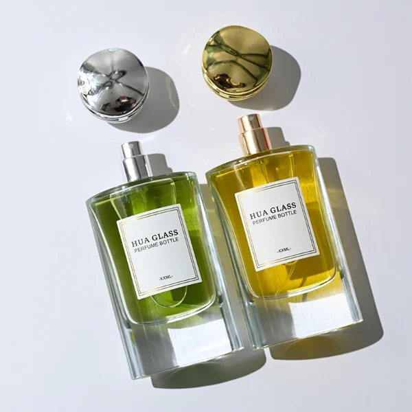 HUA0327 perfume bottle, minimalist geometric cylindrical transparent glass body with smooth curved sides and thick base, 80 ml liquid, irregular geometric plastic cap with side wave-texture in glossy gold or silver finish, printed label on bottle surface, modern minimalist luxury design, ideal for gifting and daily use.