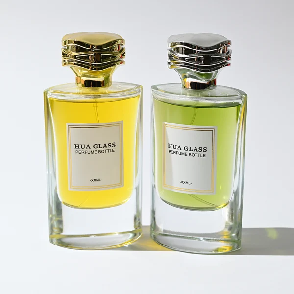 HUA0327 perfume bottle, minimalist geometric cylindrical transparent glass body with smooth curved sides and thick base, 80 ml liquid, irregular geometric plastic cap with side wave-texture in glossy gold or silver finish, printed label on bottle surface, modern minimalist luxury design, ideal for gifting and daily use.