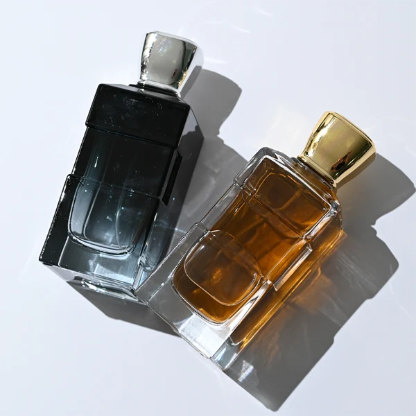 HUA0332 perfume bottle, rectangular semi-transparent gradient black or transparent colorless glass body with smooth curved edges and thick base, 100 ml liquid, rounded square-shaped glossy plastic cap in gold or silver finish, brand logo label attached on bottle surface, modern geometric luxury design, ideal for gifting and daily use.