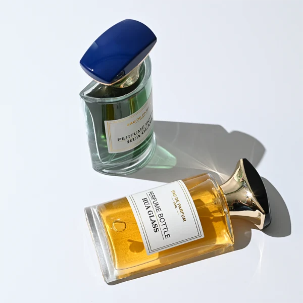 HUA0334 perfume bottle, minimalist geometric cylindrical transparent colorless glass body, 50 ml liquid, irregular geometric plastic cap with square bowl-shaped base and black or dark navy top block, no bottle neck, brand logo label attached on bottle surface, modern artistic luxury design, ideal for gifting and daily use.