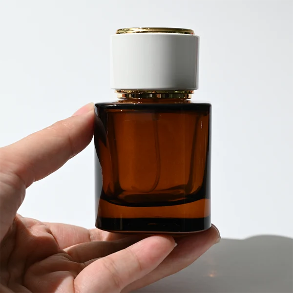 HUA0335 perfume bottle, cylindrical semi-transparent red, blue, or green glass body with thick base, 30 ml, 50 ml, or 100 ml liquid, cylindrical plastic cap with flat top and metal decorative rings on both ends, gold bottle neck, gold printed brand logo on bottle surface, modern minimalist luxury design, ideal for gifting and daily use.