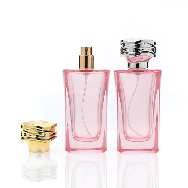 HUA0338 perfume bottle, rectangular transparent pink glass body with curved inner contour and thick base, 100 ml liquid, irregular geometric plastic cap with wave-pattern side texture in gold or silver finish, matching metallic bottle neck, clean bottle surface for logo printing or label application, elegant feminine luxury design, ideal for gifting and daily use.