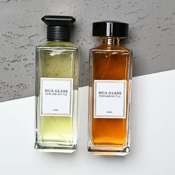 HUA0339 perfume bottle, tall rectangular transparent colorless glass body with beveled edges and thick base, 200 ml liquid, flat-top geometric plastic cap in glossy black or gold finish with layered cylindrical base, no bottle neck, brand logo label on bottle surface, modern luxury minimalist design, ideal for gifting and daily use.