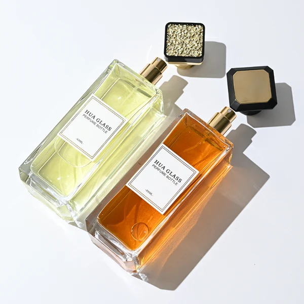 HUA0339 perfume bottle, tall rectangular transparent colorless glass body with beveled edges and thick base, 200 ml liquid, flat-top geometric plastic cap in glossy black or gold finish with layered cylindrical base, no bottle neck, brand logo label on bottle surface, modern luxury minimalist design, ideal for gifting and daily use.