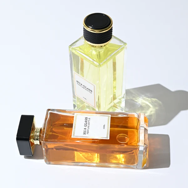 HUA0339 perfume bottle, tall rectangular transparent colorless glass body with beveled edges and thick base, 200 ml liquid, flat-top geometric plastic cap in glossy black or gold finish with layered cylindrical base, no bottle neck, brand logo label on bottle surface, modern luxury minimalist design, ideal for gifting and daily use.