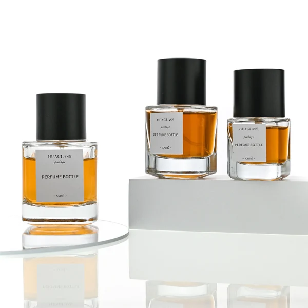 HUA0003 perfume bottles, sleek cylindrical clear glass with glossy black and white caps, golden-amber fragrance, timeless contemporary design, 30ml 50ml 100ml.