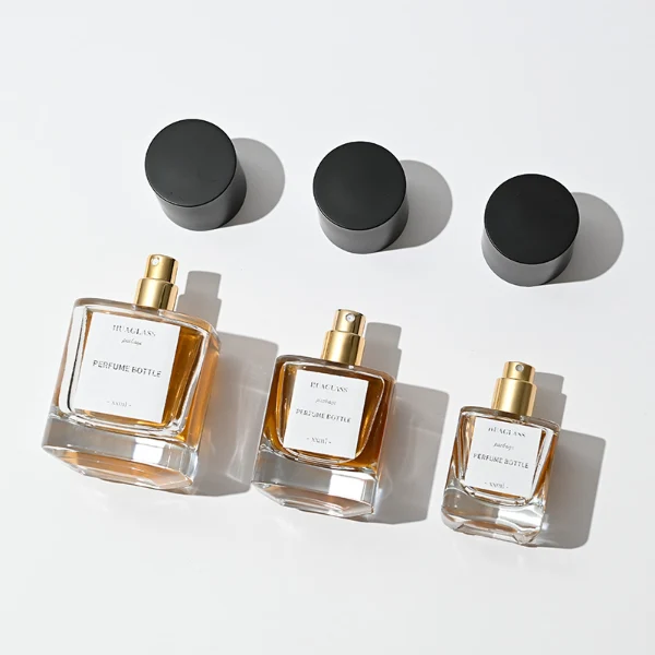 HUA0003 perfume bottles, sleek cylindrical clear glass with glossy black and white caps, golden-amber fragrance, timeless contemporary design, 30ml 50ml 100ml.