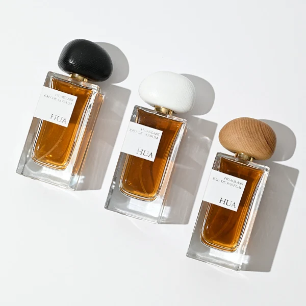 HUA0016 perfume bottle, heavy-base rectangular cuboid glass bottle with clear finish, featuring a square paper label, a polished gold neck, and an organic pebble-shaped timber cap with a natural smooth grain finish, elegant modern fragrance packaging design available in 30ml, 50ml, and 100ml