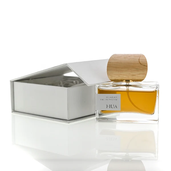 HUA0054 perfume bottle, heavy-base wide rectangular cuboid glass bottle with clear finish, featuring a gold collar neck accent and a unique horizontally oriented cylindrical barrel-shaped wood cap with subtle grain textures in a shiny charcoal black or natural light wood finish, elegant modern fragrance packaging design available in 30ml, 50ml, and 100ml.