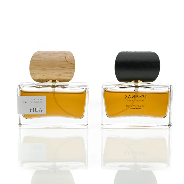 HUA0054 perfume bottle, heavy-base wide rectangular cuboid glass bottle with clear finish, featuring a gold collar neck accent and a unique horizontally oriented cylindrical barrel-shaped wood cap with subtle grain textures in a shiny charcoal black or natural light wood finish, elegant modern fragrance packaging design available in 30ml, 50ml, and 100ml.