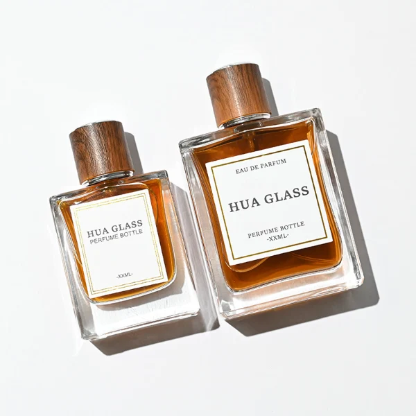 HUA0260 perfume bottle, rectangular transparent glass body with clean straight edges and thick base, 50 ml or 100 ml liquid, cylindrical wood-grain plastic cap with smooth surface and silver bottle neck, printed logo label, modern minimalist luxury design, ideal for gifting and daily use.
