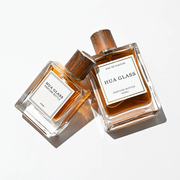HUA0260 perfume bottle, rectangular transparent glass body with clean straight edges and thick base, 50 ml or 100 ml liquid, cylindrical wood-grain plastic cap with smooth surface and silver bottle neck, printed logo label, modern minimalist luxury design, ideal for gifting and daily use.