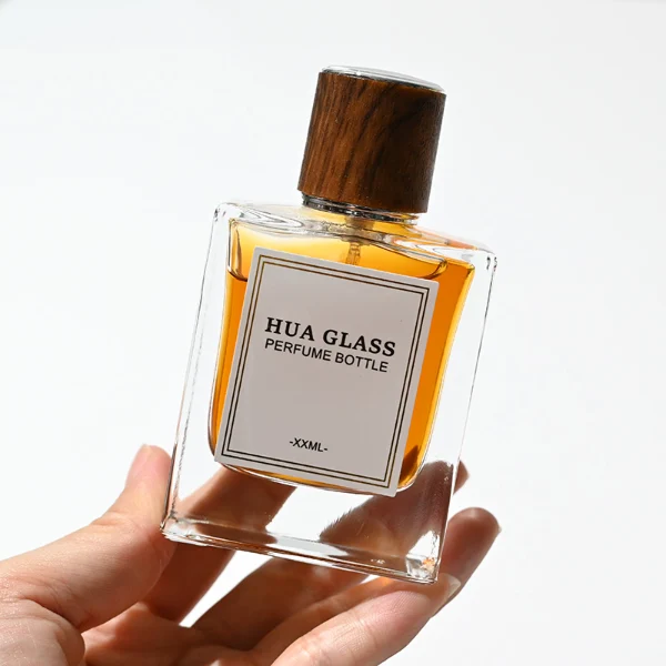 HUA0260 perfume bottle, rectangular transparent glass body with clean straight edges and thick base, 50 ml or 100 ml liquid, cylindrical wood-grain plastic cap with smooth surface and silver bottle neck, printed logo label, modern minimalist luxury design, ideal for gifting and daily use.