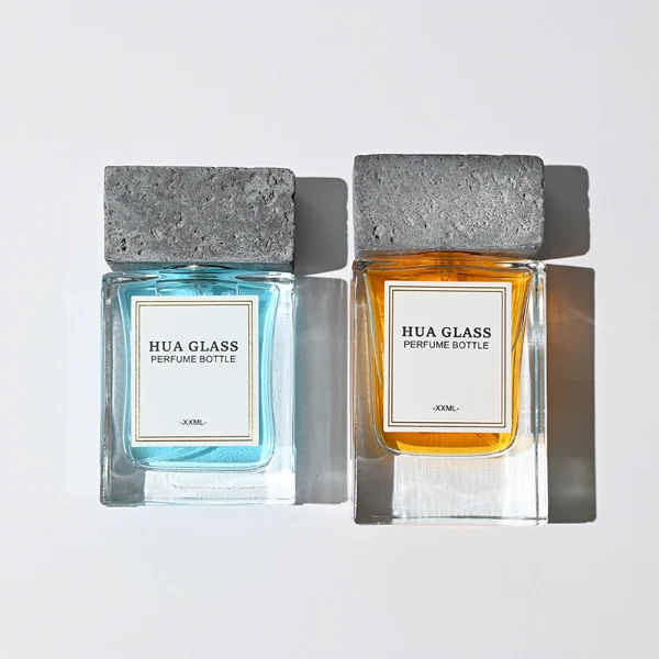 HUA0341 perfume bottle, rectangular transparent colorless glass body with thick base and curved inner contour, 50 ml liquid, oversized rectangular artificial stone cap with matte textured surface, no bottle neck, brand logo label attached on bottle surface, modern architectural luxury design, ideal for gifting and daily use.