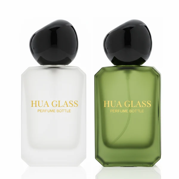 HUA0343 perfume bottle, rectangular semi-transparent blue, pink, amber, or smoky black glass body with beveled edges and thick base, 30 ml, 50 ml, or 100 ml liquid, glossy black spherical plastic cap with smooth polished surface, black bottle neck, gold printed brand logo on bottle surface, modern artistic luxury design, ideal for gifting and daily use.